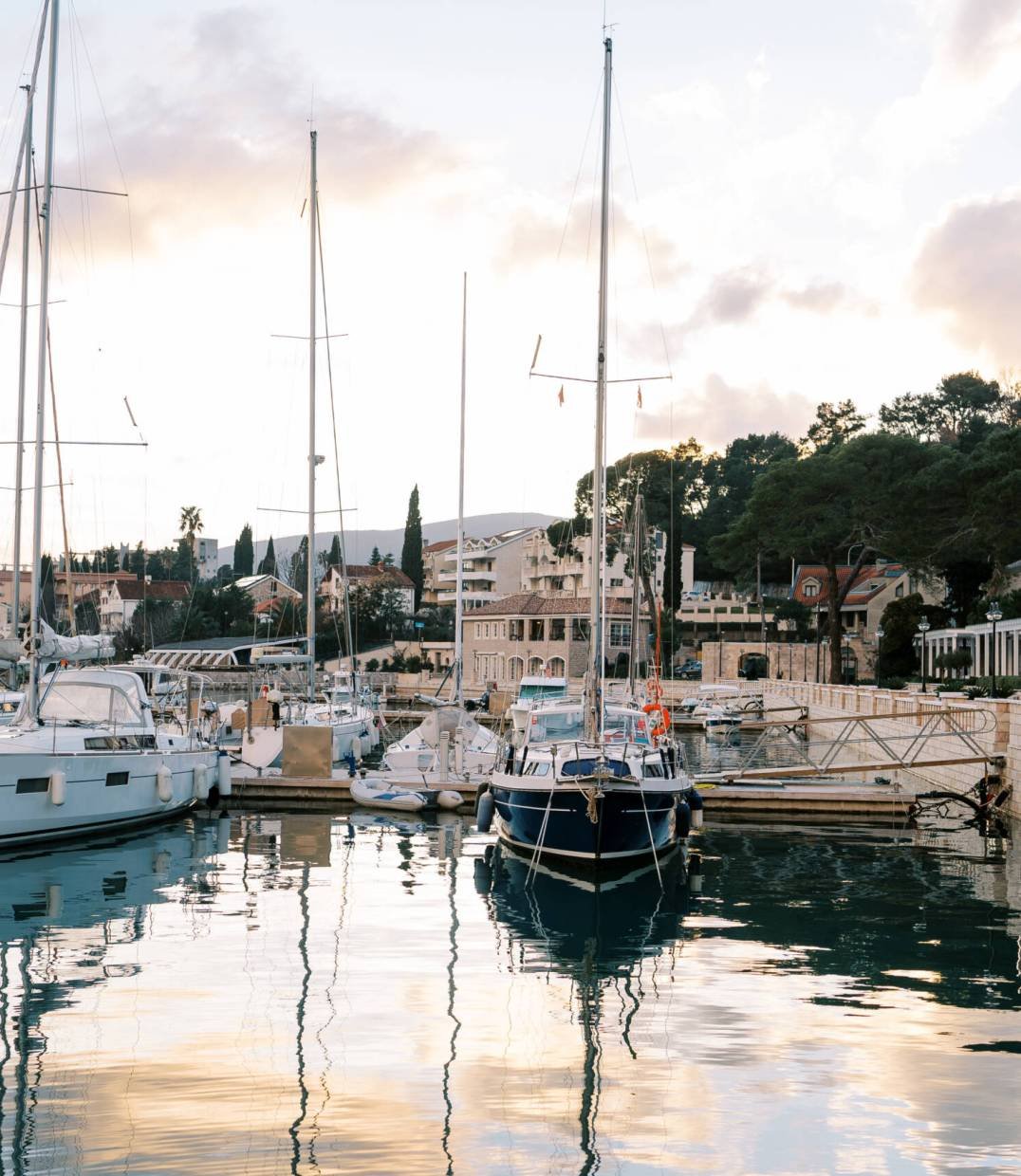 Sailing yachts are moored at the pier with colorful houses at the foot of the mountains at sunset. High quality photo